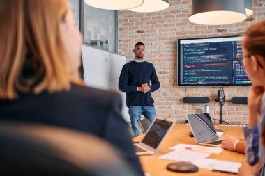 Kurumsal bir ortamda, Afrikalı-Amerikalı bir işadamı bir toplantıya liderlik eder, özenli ekibine tutkuyla bir iş planı sunar, işbirliği ve stratejik düşünmeyi teşvik eder.. 