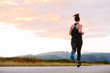 Kararlı bir sporcu güneşin altında kendinden emin bir şekilde koşar. Çevresi göz kamaştırıcı doğal manzaralarla çevrilidir. Zindelik arayışında güç ve direnç gösterir. 