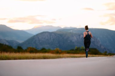 Kararlı bir sporcu güneşin altında kendinden emin bir şekilde koşar. Çevresi göz kamaştırıcı doğal manzaralarla çevrilidir. Zindelik arayışında güç ve direnç gösterir. 