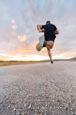 Nefes kesici bir geniş çekim kararlı bir adamı yakalar zarif bir şekilde arkaplanda koşar canlı bir günbatımının.