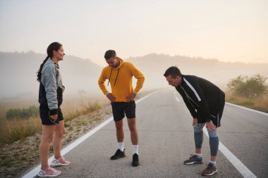 Birliğin ve hazırlığın dinamik bir gösterisinde, çeşitli sporcu grupları birlikte ısınarak zorlu bir koşu çalışmasına hazırlanıyorlar..
