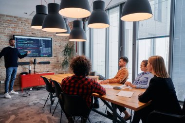 Kurumsal bir ortamda, Afrikalı-Amerikalı bir işadamı bir toplantıya liderlik eder, özenli ekibine tutkuyla bir iş planı sunar, işbirliği ve stratejik düşünmeyi teşvik eder.. 