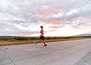 Kararlı bir sporcu güneşin altında kendinden emin bir şekilde koşar. Çevresi göz kamaştırıcı doğal manzaralarla çevrilidir. Zindelik arayışında güç ve direnç gösterir. 