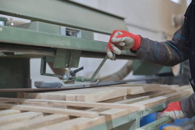 Ahşap endüstrisinde çalışan bir işçinin yakından görüntüsü. Mobilya yapımı için ahşap parçaları titizlikle kesip düzenliyor..