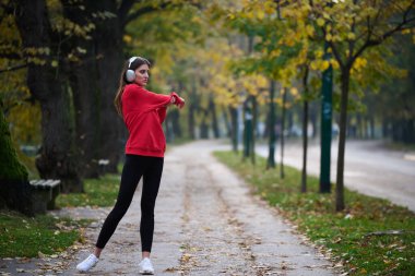 Atletik genç kadın, koşudan ve esnemeden sonra nefes alıyor ve dinleniyor. Sokakta Kadın Eğitimi ve Egzersizleri. Zayıf ve formda bir kız aktif fitness eğitiminden sonra esniyor.. 