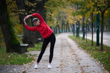 Atletik genç kadın, koşudan ve esnemeden sonra nefes alıyor ve dinleniyor. Sokakta Kadın Eğitimi ve Egzersizleri. Zayıf ve formda bir kız aktif fitness eğitiminden sonra esniyor.. 