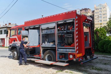 Kendini adamış bir itfaiyeci, tehlikeli bölgelerde konuşlanmak üzere modern bir itfaiye aracı hazırlıyor.. 