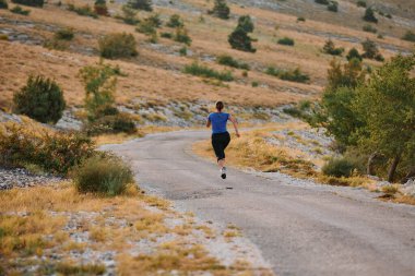 Kararlı bir bayan atlet gün doğumunda ormanda koşuyor, nefes kesici doğal güzellik ve canlı yeşillik ile çevrili.. 