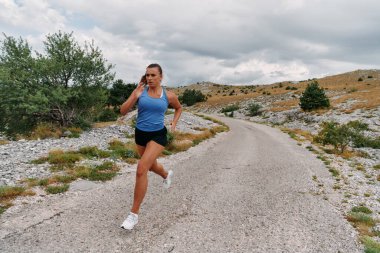 Kararlı bir bayan atlet gün doğumunda ormanda koşuyor, nefes kesici doğal güzellik ve canlı yeşillik ile çevrili.. 
