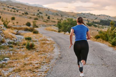 Kararlı bir bayan atlet gün doğumunda ormanda koşuyor, nefes kesici doğal güzellik ve canlı yeşillik ile çevrili.. 