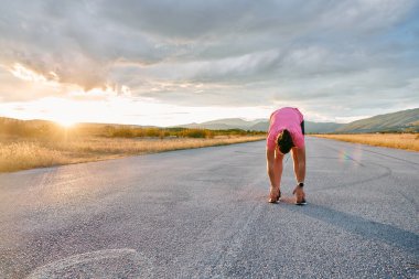 Yalnız bir sporcu, çarpıcı bir günbatımının arka planına zarifçe uzanırken yakalanır. Silueti yoğun bir koşudan sonra kendini adamışlık ve dayanıklılığın bir göstergesidir. 