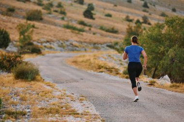 Kararlı bir bayan atlet gün doğumunda ormanda koşuyor, nefes kesici doğal güzellik ve canlı yeşillik ile çevrili.. 