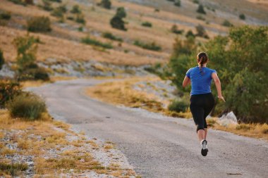 Kararlı bir bayan atlet gün doğumunda ormanda koşuyor, nefes kesici doğal güzellik ve canlı yeşillik ile çevrili.. 
