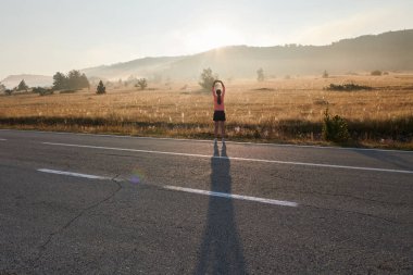  Kararlı bir atletik kadın koşudan sonra esneme hareketleri yapar, spor yolculuğuna kendini adamaya ve vücudunun esnekliğini ve esnekliğini arttırmaya çalışır.
