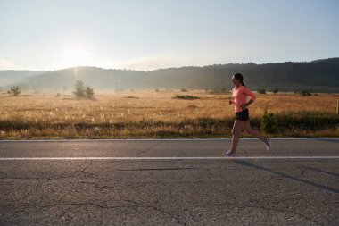 Kararlı ve motive olmuş bir sporcu gün doğumuna güvenle koşuyor, sabah koşusunda kararlılığını ve gücünü özetliyor.. 