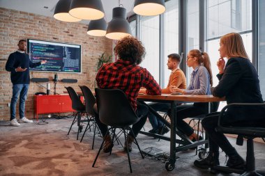 Kurumsal bir ortamda, Afrikalı-Amerikalı bir işadamı bir toplantıya liderlik eder, özenli ekibine tutkuyla bir iş planı sunar, işbirliği ve stratejik düşünmeyi teşvik eder.. 