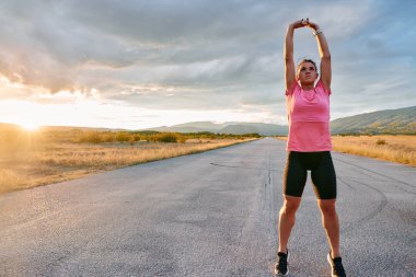 Yalnız bir sporcu, çarpıcı bir günbatımının arka planına zarifçe uzanırken yakalanır. Silueti yoğun bir koşudan sonra kendini adamışlık ve dayanıklılığın bir göstergesidir. 