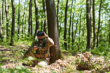 Son model VR gözlükleriyle donatılmış seçkin bir asker askeri bir drone 'u manevra yaparak modern savaş teknolojisinin kusursuz bütünleşmesini gösteriyor..