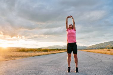 Yalnız bir sporcu, çarpıcı bir günbatımının arka planına zarifçe uzanırken yakalanır. Silueti yoğun bir koşudan sonra kendini adamışlık ve dayanıklılığın bir göstergesidir. 