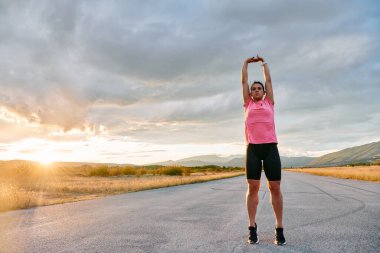 Yalnız bir sporcu, çarpıcı bir günbatımının arka planına zarifçe uzanırken yakalanır. Silueti yoğun bir koşudan sonra kendini adamışlık ve dayanıklılığın bir göstergesidir. 