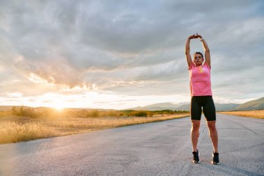 Yalnız bir sporcu, çarpıcı bir günbatımının arka planına zarifçe uzanırken yakalanır. Silueti yoğun bir koşudan sonra kendini adamışlık ve dayanıklılığın bir göstergesidir. 