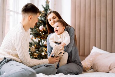 Mutlu, genç bir aile. Anne ve baba, küçük kızıyla birlikte Noel ağacının yanında. Eğlen, mutlu aile hayatının tadını çıkar. Yaşam tarzı kavramı.