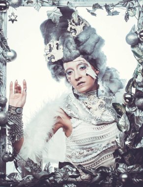 Parti, Noel ve halk konsepti: Gümüş sanatsal makyajlı, peruklu, Noel süslemeleri ile süslenmiş gümüş çerçevede poz veren yaratıcı görünümlü genç kadın. Kış Portresi. Kar Kraliçesi.