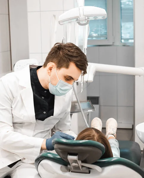 People, medicine, stomatology, technology and health care concept. Professional dentist working with little girl in clinic.