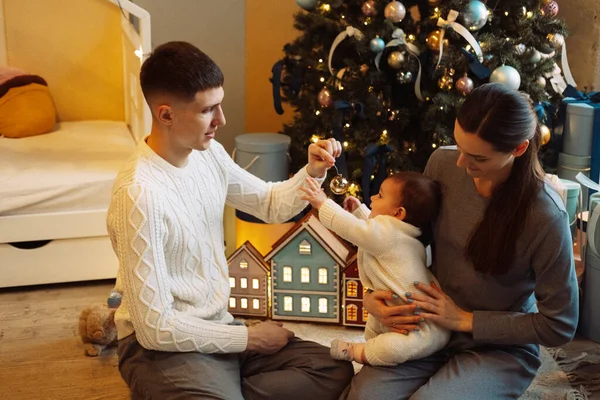happy father standing near wife holding cute little daughter, family and christmas concept