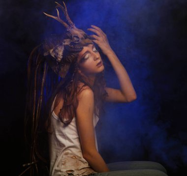 Parlak makyajlı, örgülü saçlı ve kafasında siyah bir arka planda poz veren güzel bir genç kadın. Karnaval partisi, Cadılar Bayramı konsepti.