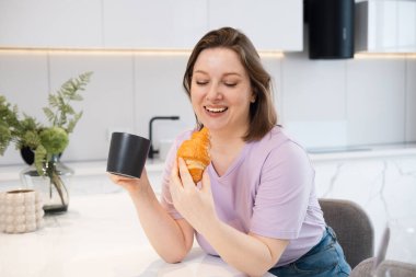 Cazibeli, kahve içen ve sabahın erken saatlerinde mutfakta kruvasan yiyen çekici bir kadın. Kendini ve mutlu bir hayatı kabul etme kavramı..