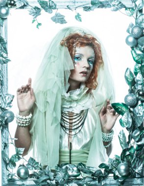 Noel karnavalı için kostüm giymiş güzel bir kızıl kadın Noel süsleri ve gümüş yapraklar çerçevesinde poz veriyor. Yaratıcı makyaj, saç stili. Kış stili, Kar Kraliçesi.