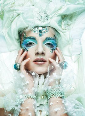 Parti, noel ve halk konsepti: mavi sanatsal makyajlı genç kadın. Kış Portresi. Kar Kraliçesi.