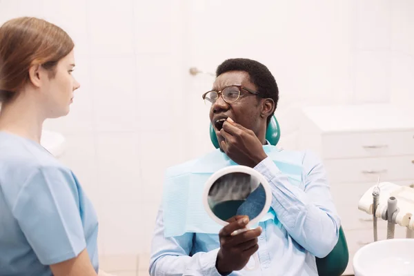 在与女牙医检查时出现牙齿疼痛的黑人男性患者 在现代诊所接受专业口腔科治疗的年轻非洲裔美国男性 特写镜头 — 图库照片