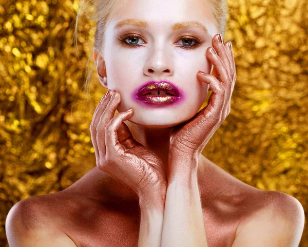 唇にはっきりと描かれた目と金によって人の輝く滑らかな健康的な肌を持つ若い女性の顔の肖像画 黄金の背景 — ストック写真
