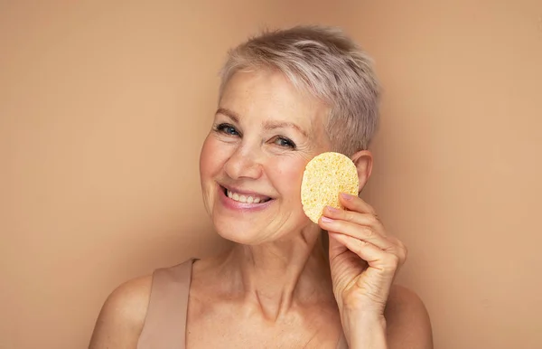Photo Nice Old Woman Use Sponge Remove Make Beige Background — Stock Photo, Image
