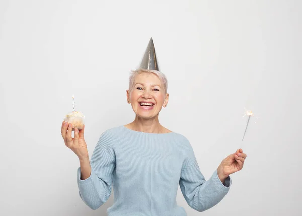 党和老年人的概念 中年妇女头戴圆锥帽 头戴蜡烛 头戴灰色背景的火花 庆祝生日 快乐无比 — 图库照片