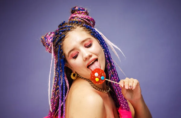 一个年轻的女人 有着可怕的发型和富有创意的化妆 洋娃娃风格 背景是紫色的糖果 — 图库照片