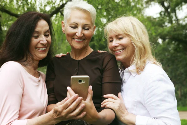 Три Пожилые Женщины Улыбаются Смотрят Фотографии Экране Телефона Парке Летний — стоковое фото