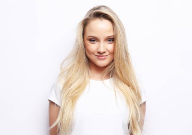 Çekici, sarışın, günlük kıyafetler giyen, beyaz arka planda izole edilmiş genç bir kadın, kameraya bakıyor.