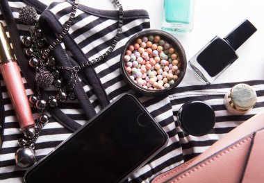 Kozmetik ürünleri, aksesuarlar ve beyaz arka planda akıllı telefonlu pembe deri kadın çantası.