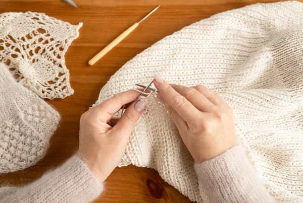 Üst düzey kadın elleri beyaz yünlü örgü örüyor, üst manzara, yakın çekim.