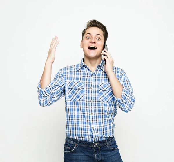 年轻英俊的男人穿着蓝色格子呢衬衫 在白色背景的手机上打手势微笑 — 图库照片