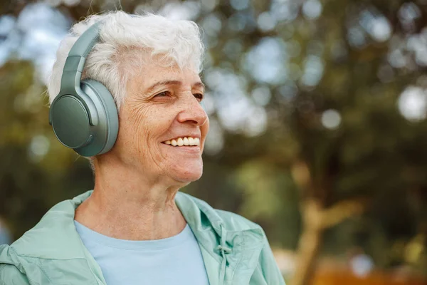 公園で音楽を聴くヘッドフォンの老婦人 高齢者についての概念 高齢者や健康の高齢化 — ストック写真