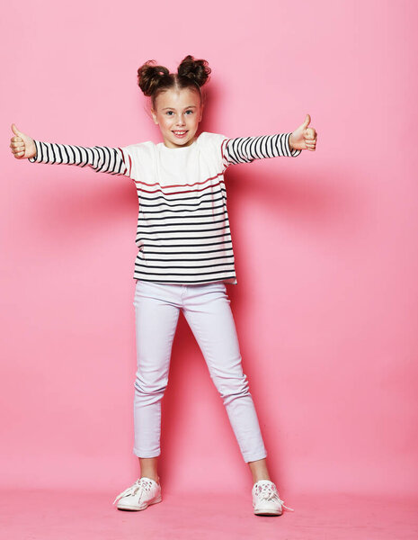 Adorable little girl with curly hairstyle posing on pink background. Close up portrait.