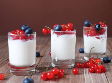 İyi sabahlar. Sağlıklı kahvaltı - beyaz yoğurt, cam kavanozda taze böğürtlen, ahşap arka planda.