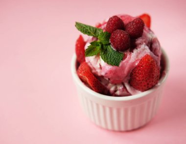 Bir kase pembe çilekli dondurma ve pembe arka planda izole edilmiş taze böğürtlen. Üst Manzara. Pembe arkaplan.