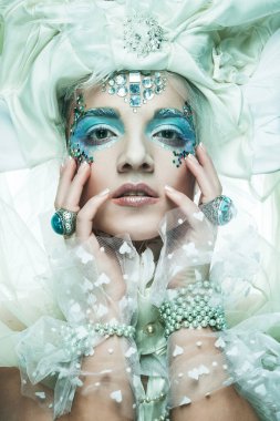 Parti, noel ve halk konsepti: mavi sanatsal makyajlı genç kadın. Kış Portresi. Kar Kraliçesi.