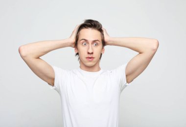 Beyaz tişört giyen genç adam korkmuş ve şaşkınlık dolu bir ifade, korku ve heyecan dolu bir yüz ifadesiyle şok olmuştu. Yaşam tarzı ve insan kavramı.