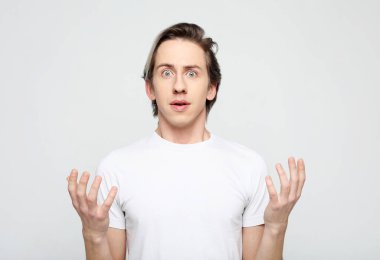 Yaşam tarzı, duygu ve insan konsepti: gri saçlı genç bir adamın portresi yüz ifadesini şaşırttı, gri arkaplan üzerinde yakın plan portresi